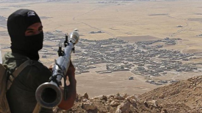 Một tay súng người Kurd quan sát làng Baretle – đang nằm trong tay IS. Ảnh: Reuters