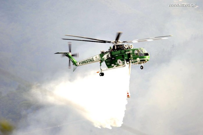 Trực thăng phun nước dập lửa nơi 2 chiếc máy bay bốc cháy. Ảnh: News.cn