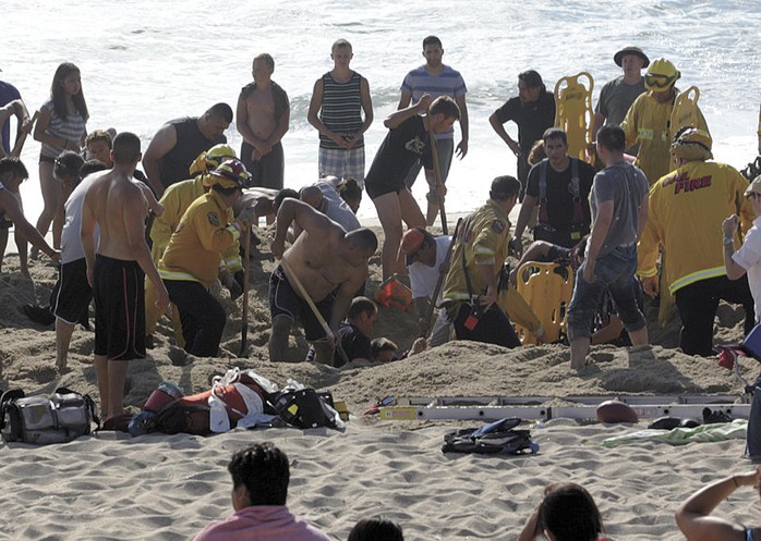30 người có mặt tại bãi biển tích cực đào bới cứu chàng trai nhưng không kịp. Ảnh: AP