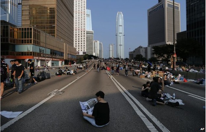 A woman sits and reads the newspaper in the middle of a street which pro-democracy activists have made camp at, Tuesday, 30 Sept 2014 in Hong Kong. 