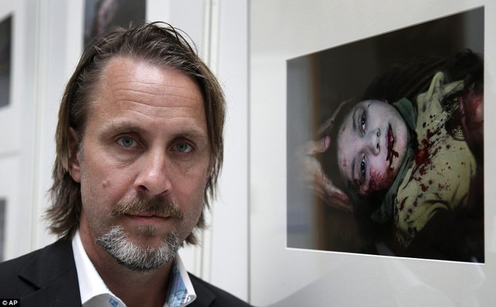 Award: Niclas Hammarstrom from Sweden poses in front his photograph, the winner of Unicef Photo of the Year 2013, which he captured while spending 24 hours documenting the work of medics at Dar-al-Shifa hospital. The photo shows Danias head being cradled in her oldest brothers hands while her wounds are dressed