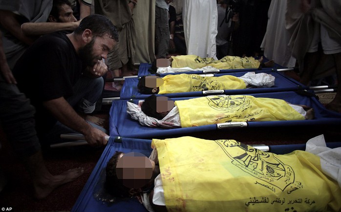 Death: Palestinians mourn over the dead bodies of four boys from the same family, who were killed by an Israeli airstrike on a beach in Gaza today. The boys&apos; bodies were covered with the yellow flags of the Fatah movement while displayed in a mosque ahead of their funeral this afternoon