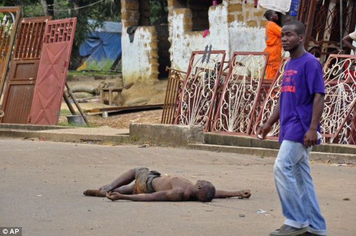 Shocking: Relatives of Ebola victims in Liberia have started dragging their loved ones bodies out of their homes and dumping them on the streets in a bid to avoid being quarantined. Above, a man walks past the dead body