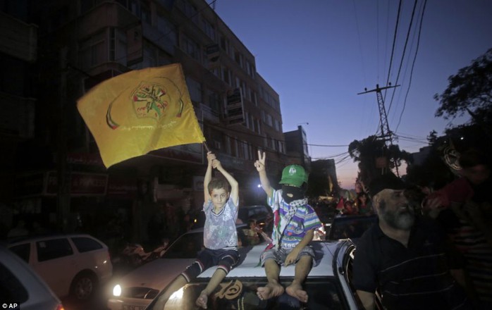 Getting involved: Two Palestinian children sit atop a car. One holds a yellow Fatah movement flag to celebrate the ceasefire, while the other makes a victory sign