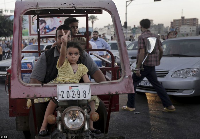 Young supporter: The truce took effect at 7 p.m. local time (1600 GMT). Above, a Palestinian girl makes the victory sign as she sits on her fathers lap yesterday