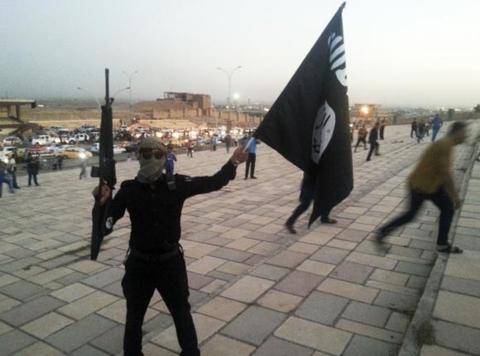 Một chiến binh IS vẫy cờ của tổ chức trên đường phố Mosul - Iraq ngày 23-6. Ảnh: Reuters