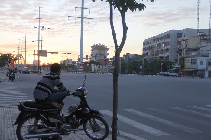 Một anh xe ôm cô độc ngồi nhìn thành phố vắng lặng