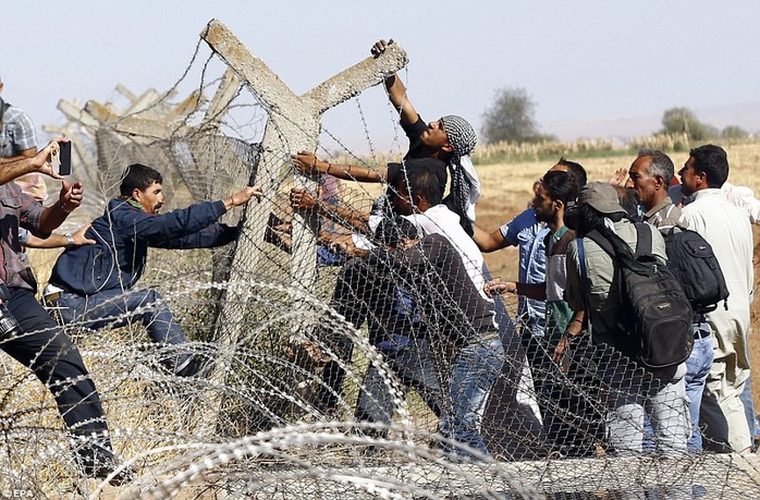 Người Kurd xô đổ hàng rào ở biên giới Thổ Nhĩ Kỳ, đòi gia nhập lực lượng chống IS ở Kobane. Ảnh: EPA