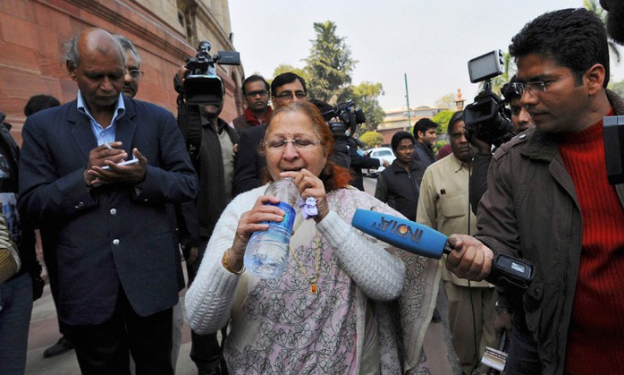 Nữ nghị sĩ Sumitra Mahajan vội vã uống nước sau khi thoát khỏi cuộc loạn đả. Ảnh: Reuters