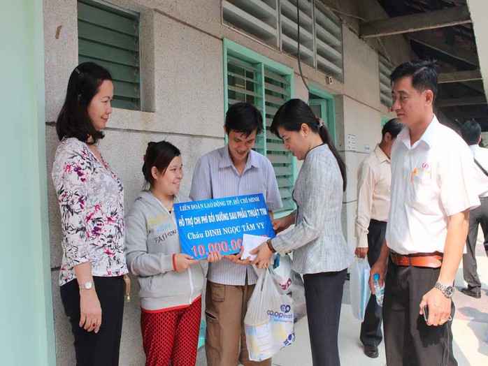 Bà Nguyễn Trần Phượng Trân, Phó Chủ tịch LĐLĐ TP (thứ hai từ phải sang), trao tiền cho gia đình anh Hiếu