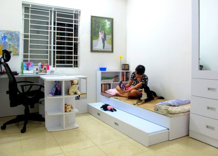 Góc làm việc có tủ thiết kế thành nhiều ô để đựng đồ trang trí. Chiếc giường trắng có thể kéo ra đủ chỗ cho hai người nằm và có thể dựng lên hay chuyển sang phòng khác. Góc làm việc có tủ thiết kế thành nhiều ô để đựng đồ trang trí. Chiếc giường trắng có thể kéo ra đủ chỗ cho hai người nằm và có thể dựng lên hay chuyển sang phòng khác.