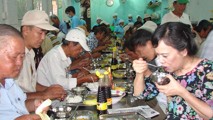 Bà Mai Thị Hạnh (bìa phải) dùng cơm với người nghèo trưa 4-7 - Ảnh: M.Hương