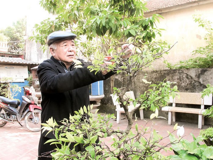 Đại tá Hoàng Đăng Vinh chăm sóc hoa cảnh trong vườn nhà. Ảnh: VĂN DUẨN