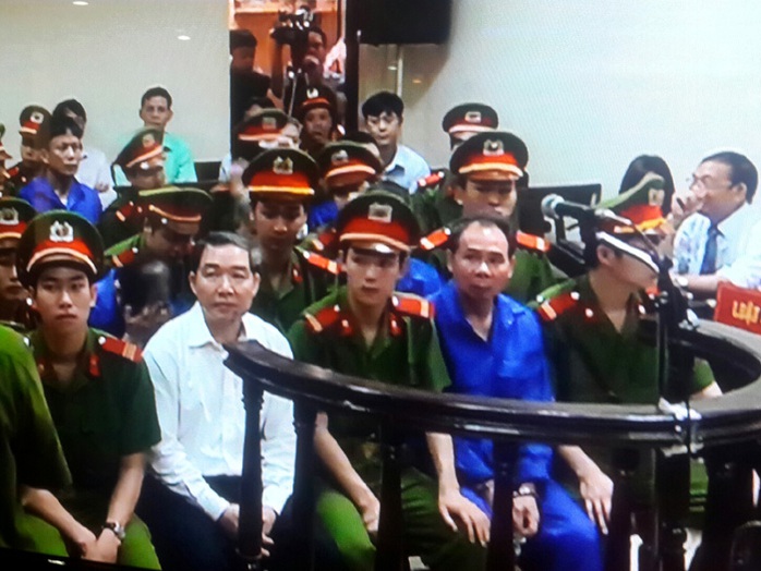 Dương Chí Dũng diện sơ mi trắng, sơ vin (ngồi hàng đầu) trong khi Mai Văn Phúc mặc đồng phục màu xanh (ngôi hàng đầu) như các bị cáo khác tại tòa phúc thẩm - Ảnh chụp qua màn hình