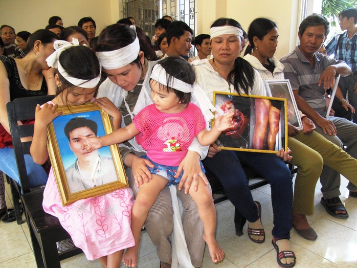 Gia đình bị hại mang theo di ảnh nạn nhân cùng hình ảnh chụp hậu quả việc dùng nhục hình - Ảnh: Hồng Ánh