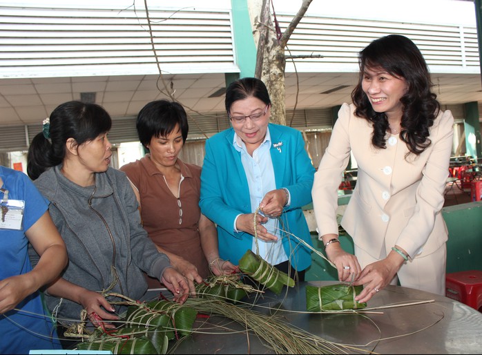 Bà Nguyễn Thị Thu, Chủ tịch LĐLĐ TP (phải) và bà Nguyễn Thị Bích Thủy, Phó Chủ tịch LĐLĐ TP (thứ hai, bên phải) gói bánh tét cùng công nhân