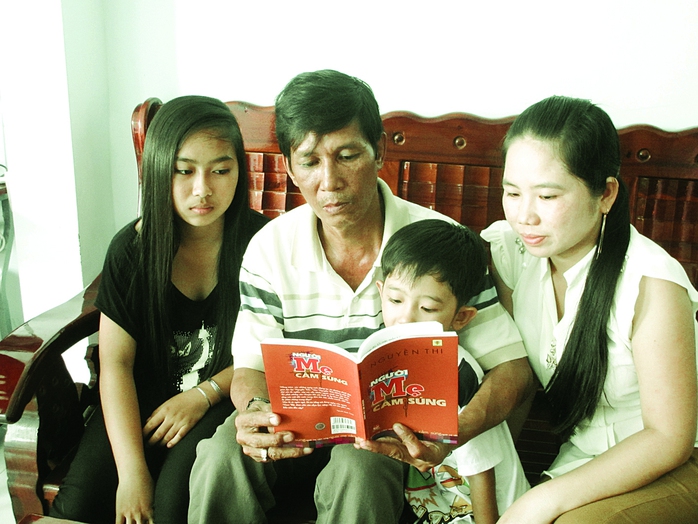 Gia đình anh Lâm Thanh Hiển quây quần đọc truyện Người mẹ cầm súng. Ảnh: LÊ CHINH