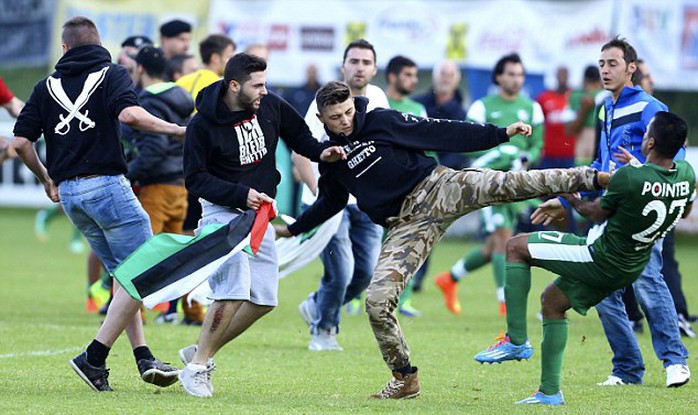 Cầu thủ của Maccabi Haifa (áo xanh) bị người biểu tình đá vào ngực