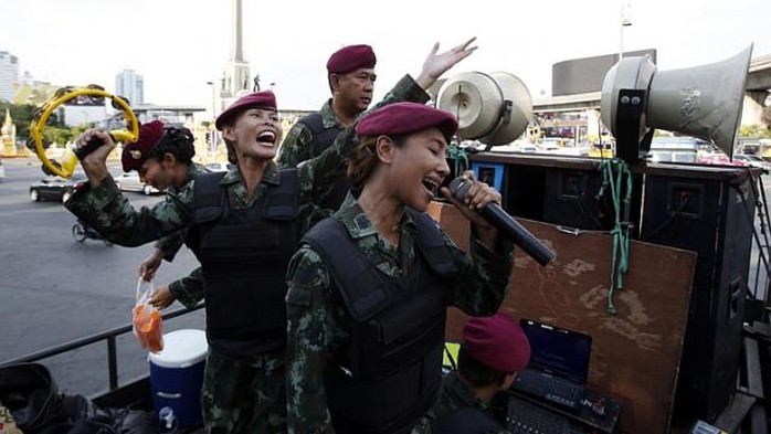 Nữ binh sĩ Thái Lan dùng âm nhạc xoa dịu người biểu tình hôm 3-6. Ảnh: Reuters