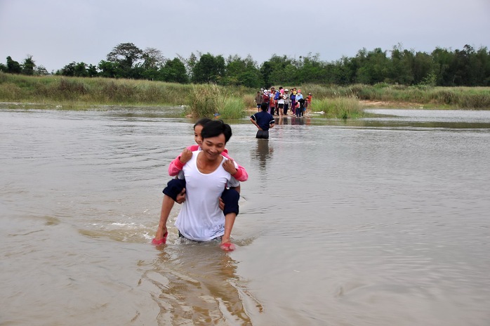 Lũ trên sông Trà Khúc đang lên cao, nhiều người dân cõng con đến trường, lội qua dòng nước chảy xiết