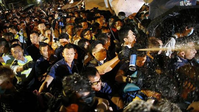 Cảnh sát xịt hơi cay vào người biểu tình rạng sáng 16-10. Ảnh: Reuters