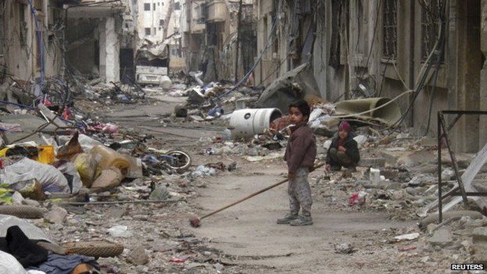 A child clears damage and debris in the besieged area of Homs on 26 January 2014