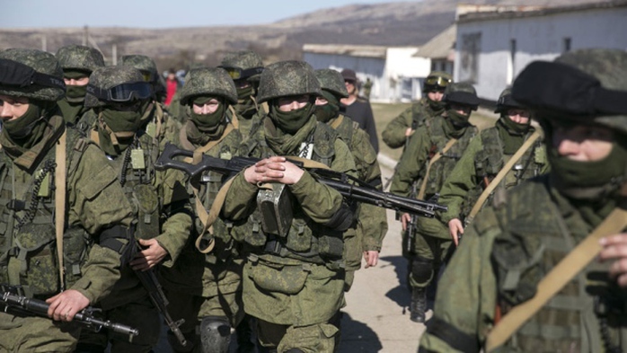 Military personnel, believed to be Russian servicemen, walk outside the territory of a Ukrainian military unit in Crimea. A Ukrainian mission to the United Nations claims 16,000 Russian troops have massed in Crimea.