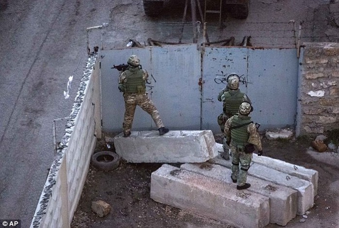 Unidentified armed men search an area close to an Ukrainian military unit in Simferopol, after  gunfire at the military facility in the capital of separatist Crimea killed one serviceman and a member of a local self-defense brigade
