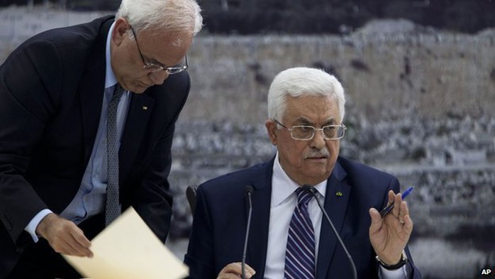 Palestinian President Mahmoud Abbas, right, joined by Palestinian chief peace negotiator Saeb Erekat, signs an application to the UN agencies in the West Bank city of Ramallah, on 1 April 2014. 