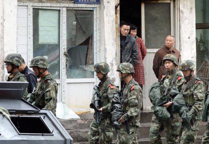 Armed policemen patrol past a building whose window was damaged by an explosion in Urumqi, northwest Chinas Xinjiang region, on Thursday.