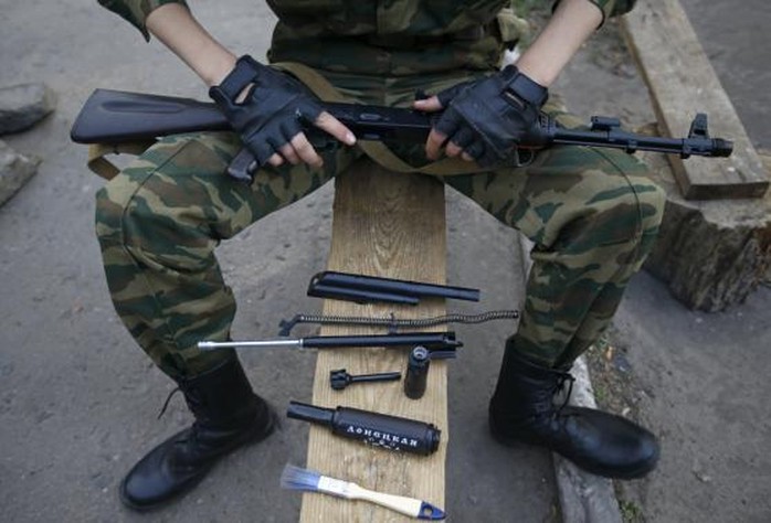 A pro-Russian armed man, with the parts of his weapon laid out on a bench, poses for a picture at a checkpoint in Slaviansk, eastern Ukraine May 23, 2014. REUTERS/Maxim Zmeyev