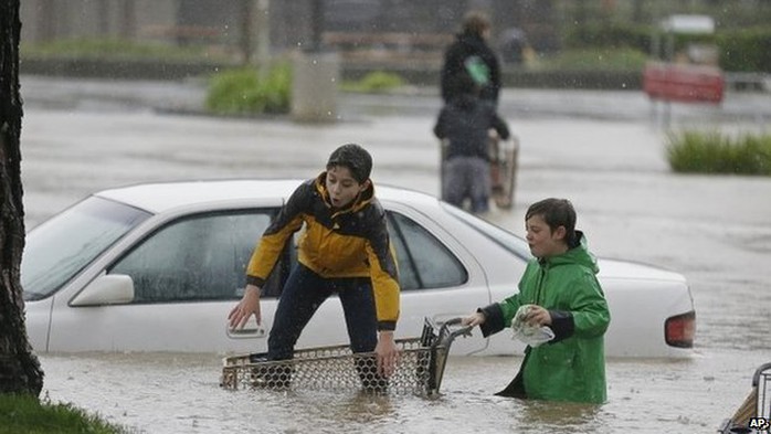 Aidan Perez, left, 12, and Christopher Dow, right, 11, use a shopping cart to get around the flooded parking lot of a shopping center Thursday, Dec. 11, 2014, in Healdsburg, California 11December 2014