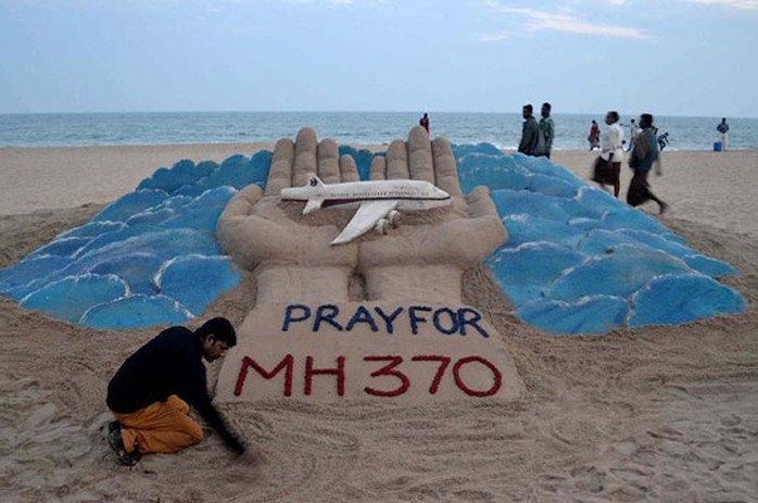 Nghệ sĩ điêu khắc cát Sudarshan Pattnaik bên tác phẩm cầu nguyện cho chuyến bay mất tích MH370 trên bãi biển ở Puri - Ấn Độ. Ảnh: Stringer
