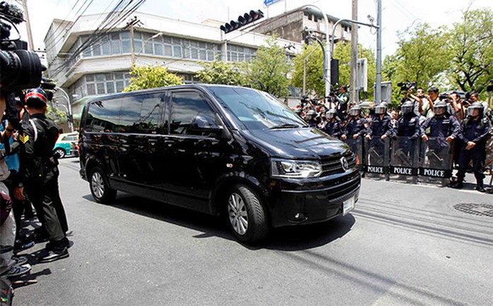 Bà Yingluck đến địa điểm trình diện ở khu vực Thewes, Bangkok trên một chiếc xe chống đạn Volkswagen màu đen có đội vệ sĩ đi kèm. Ảnh: Reuters