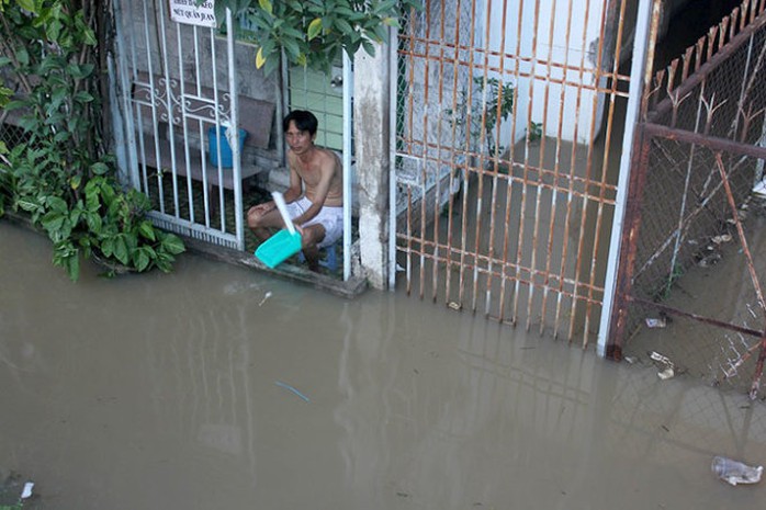 Người dân trên đường Huỳnh Tất Phát, huyện Nhà Bè ngồi trước cửa nhà để tát nước do triều cường gây ngập ngày 10-10-2014 - Ảnh: Đức Phú