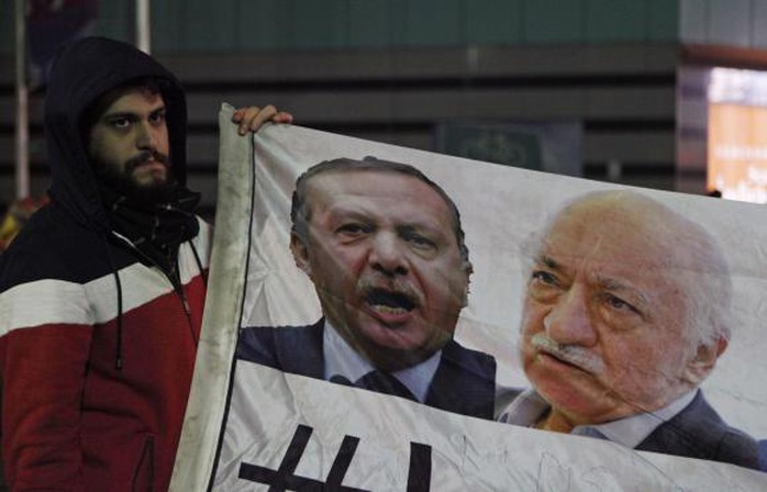 Một người biểu tình cầm hình ảnh Thủ tướng Erdogan và giáo sĩ Fethullah Gulen.
Ảnh: Reuters