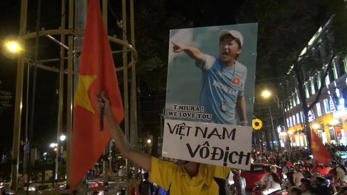 Người đàn ông cầm tấm hình của HLV Miura, bên dưới có dòng chữ Việt Nam vô địch