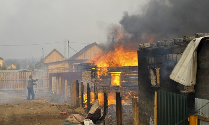 Một người đàn ông cố gắng dập lửa ở ngôi nhà của mình tại Smolenka, Siberia nhưng sau cùng nó cũng bị thiêu rụi. Ảnh: AP