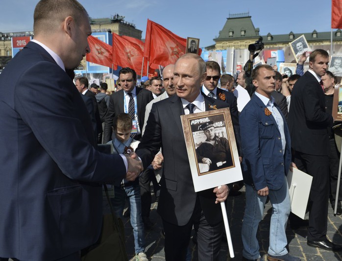 Tổng thống Nga Vladimir Putin (giữa) cầm di ảnh cha tham dự duyệt binh tại Quảng trường Đỏ hồi tháng 5 vừa qua. Ảnh: Reuters