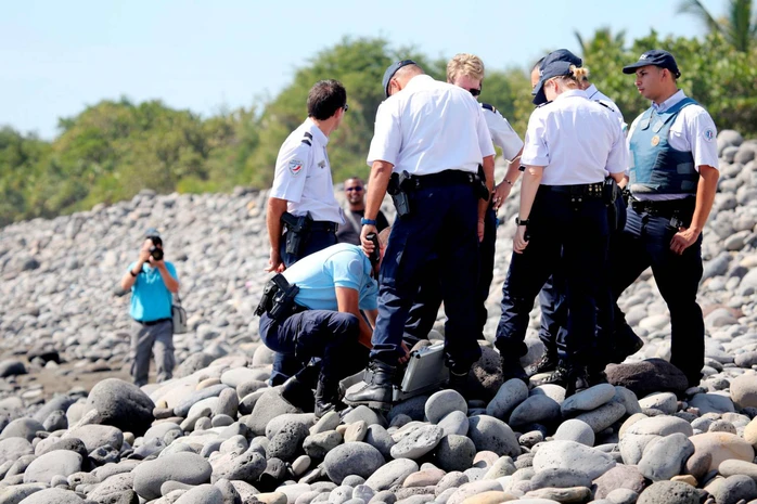 Police officers inspect metallic debris found on a beach in Saint-Denis on the French Reunion Island