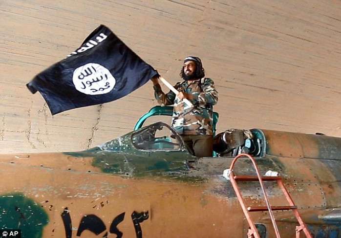 An Isis fighter waves the groups flag from inside a captured government fighter jet in Raqqa
