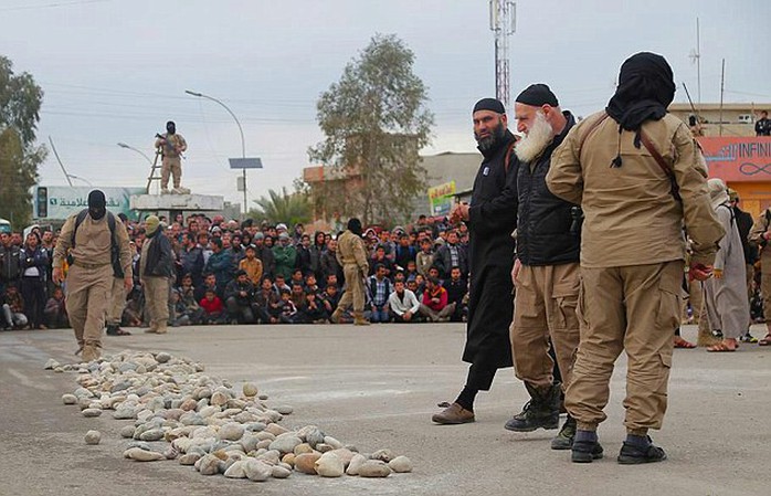 Preparing to kill: After the charges are read out, the familiar white-bearded face of ISIS' elderly Mosul-based executioner-in-chief Abu Ansar al-Ansari (centre) orders their stoning to death