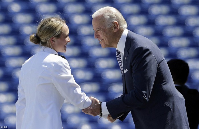 Holding on: Biden leans in to one female graduating member of the academy and grins as he shakes her hand