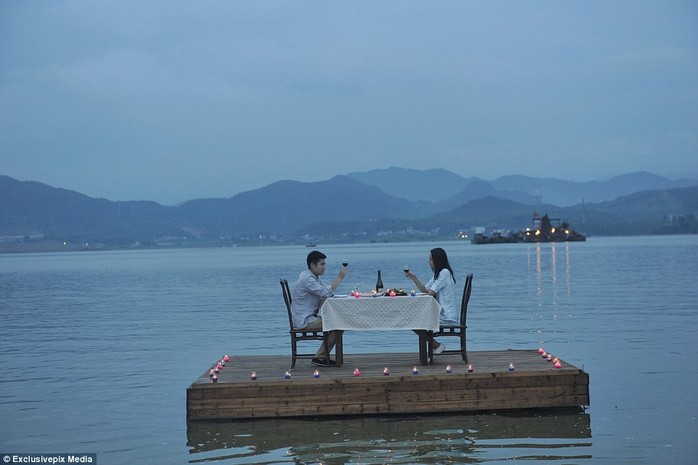 A boat, which brings the two diners to their floating wooden platform, remains anchored nearby so that waitstaff can serve the couple
