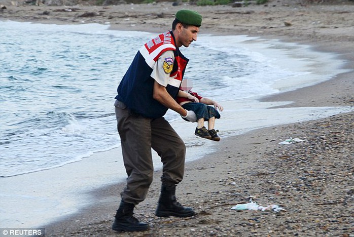 A policeman on a Turkish beach gently recovers the body of Aylan who drowned as his family tried to make their way to the Greek island of Kos yesterday