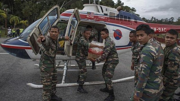 Quân lính Malaysia đang chuyển hàng lên trực thăng cứu trợ. Ảnh Reuters