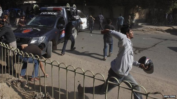 A protester throws stones with others at policemen during a protest in Karachi January 16
