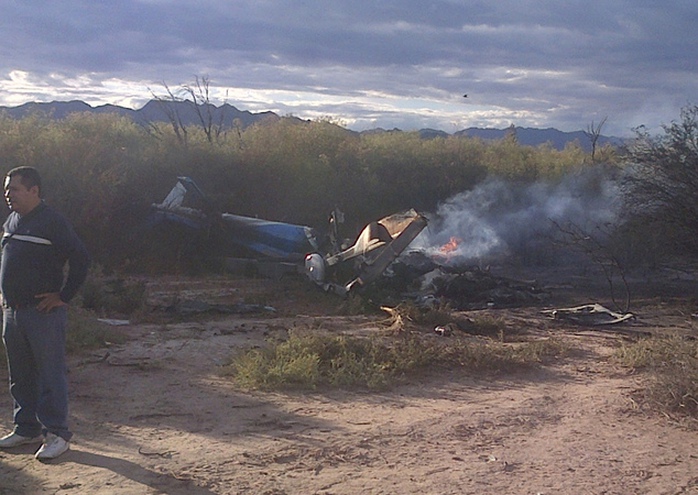 A man stands near one of two helicopters that crashed near Villa Castelli in the La Rioja province of Argentina, Monday, March 9, 2015. Two helicopters with ...