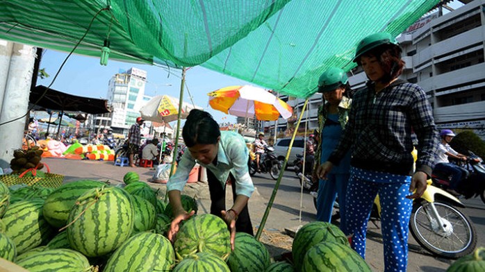 Quầy hàng dưa hấu của chị Nguyễn Thị Nhị trên đường Phan Đăng Lưu quảng cáo giá bán 12.000 đồng/kg nhưng khách trả 10.000 đồng/kg chị cũng bán -  Ảnh: Thanh Tùng