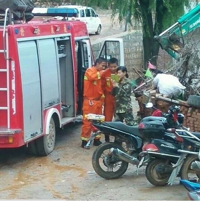 Ba lính cứu hỏa túm tụm đứng chụp hình... Ảnh: The Nanfang